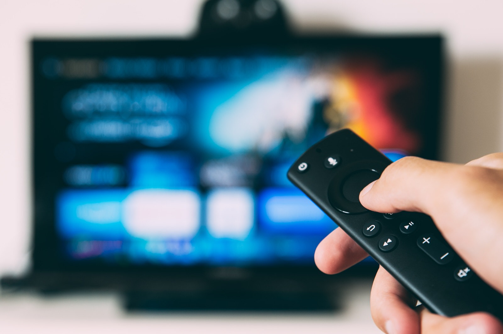 Person holding remote in front of television screen