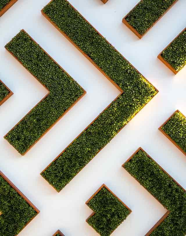 Textural architectural detail  of chevron shaped wall planter boxes full of greenery. 